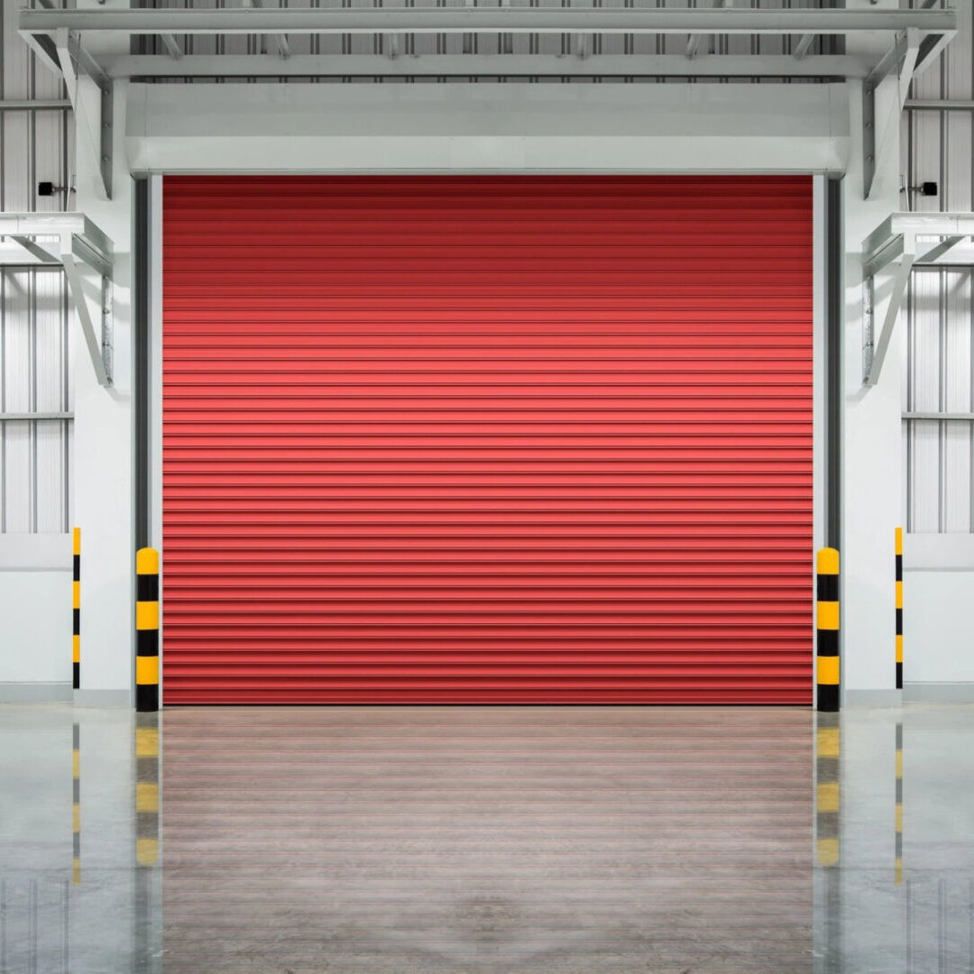 inside a silver white steel building with a red garage door